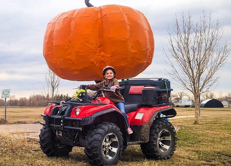 girl on atv in front of large pumpkin